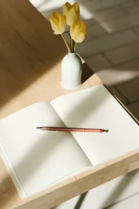 journal on the table with some flowers in the pot